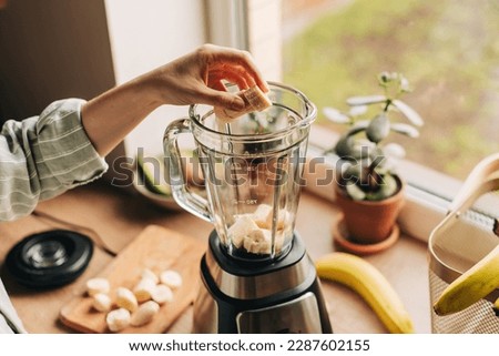 Woman is preparing a healthy detox drink in a blender - a smoothie with fresh fruits and avocado. Healthy eating concept, ingredients for smoothies on the table, top view