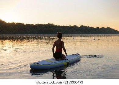 A woman preparing her paddleboard for her morning yoga workout on a calm river