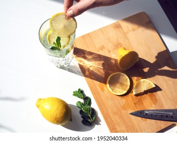Woman preparing lemon water. Detox water with mint and lemon. Refreshing summer drink. Wellness, diet, healthy eating concept