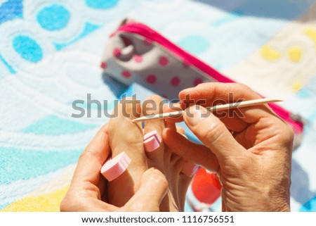 Woman preparing nails before pedicure. Unrecognizable female pushing her cuticle skin during outdoor vacations.