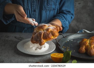 Woman preparing Pan de muertos bread of the dead for Mexican day of the dead.