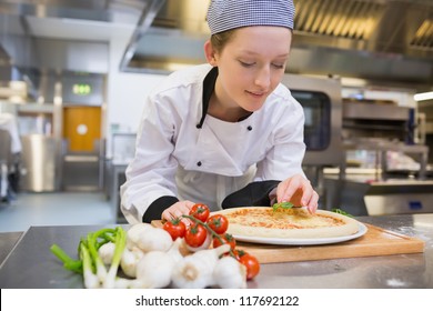 Woman preparing pizza in kitchen