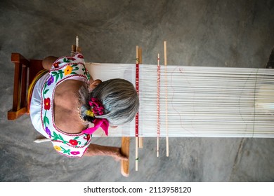 Woman preparing to produce a beautiful cotton fabric using the traditional method of waist weaving.