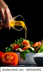 Woman preparing a salad with tomatoes, lettuce, olive oil and salt Concept of healthy diet