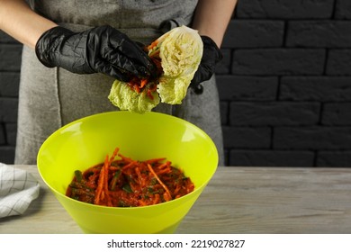 Woman Preparing Spicy Cabbage Kimchi At Wooden Table Indoors, Closeup