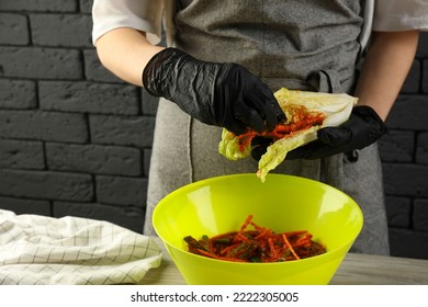 Woman Preparing Spicy Cabbage Kimchi At Wooden Table Indoors, Closeup