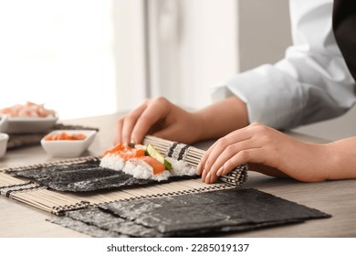 Woman preparing sushi rolls at table - Powered by Shutterstock