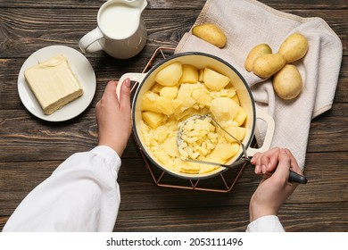 Woman preparing tasty mashed potatoes on wooden background, closeup - Shutterstock ID 2053111496