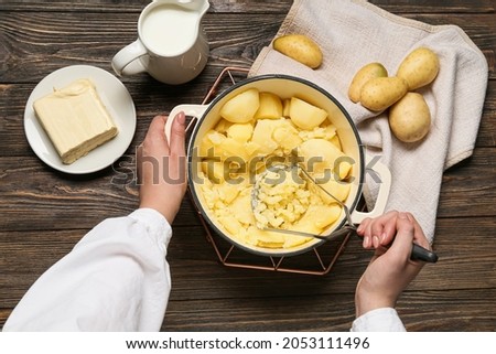 Woman preparing tasty mashed potatoes on wooden background, closeup