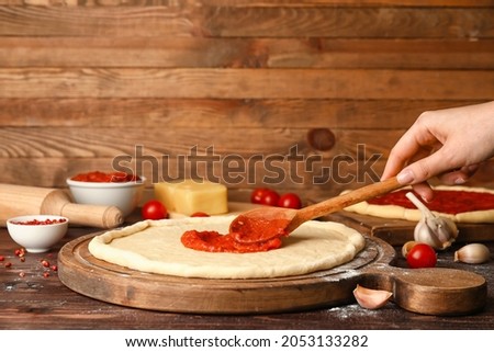 Woman preparing tasty pizza on wooden table