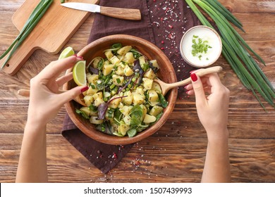 Woman preparing tasty salad at table, top view