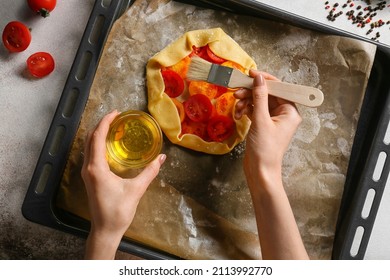 Woman preparing tasty tomato galette at table - Shutterstock ID 2113992770