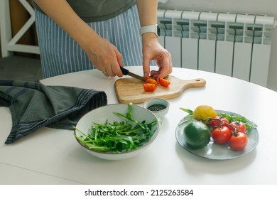 Woman preparing vegetable salad with tomato in the kitchen. Healthy food vegan salad. Mindful eating. - Shutterstock ID 2125263584
