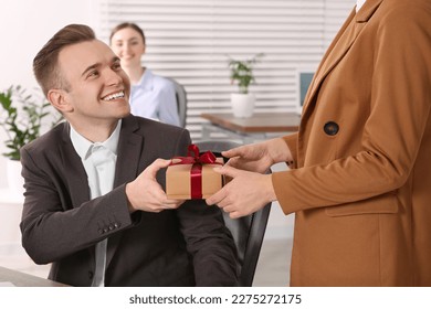 Woman presenting gift to her colleague in office - Powered by Shutterstock