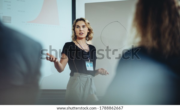 Woman presenting her\
idea to colleagues in meeting. Businesswoman public speaking in a\
conference meeting.