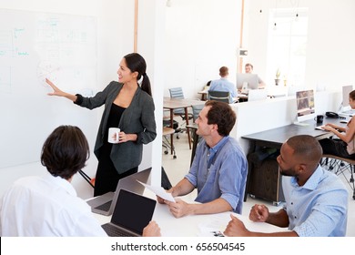 Woman Presenting A Meeting At A Whiteboard In A Busy Office