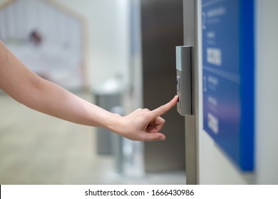 Woman press on elevator control panel in the building to call the elevator. Woman using elevator to reach higher floor in high building.