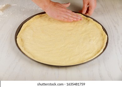 Woman Presses On Fresh Raw Pizza Dough In Oven Pan.