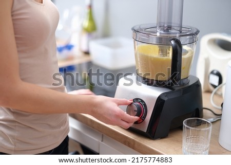 Woman presses start of food processor with dough