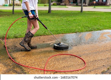 Woman Pressure Washing To Clean Driveway Of A Home