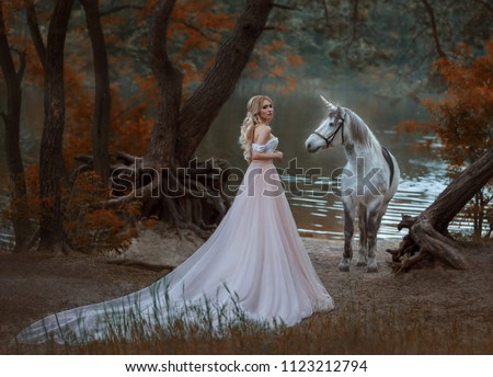 Woman princess met unicorn horse with Horn. Fairy forest autumn tree. lake river fog. blonde girl angelic face elegant hairstyle medieval white clothing long vintage dress skirt train. Artistic Photo