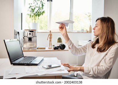 Woman procrastinate at workplace. Freelancer on remote work at home office. Unmotivated tired woman play with paper plain. Lazy office worker