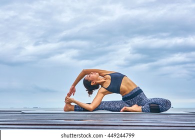 A woman professional trainer yoga pose on wooden bridge over seaside. - Powered by Shutterstock