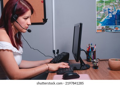 Woman In Profile Working At Her Work Desk. Woman Working In A Travel Agency. Red-haired Woman Working On The Computer In Her Office. High Quality Photo