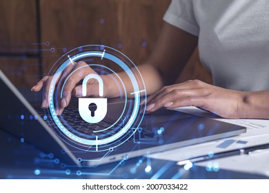 A woman programmer is typing a code on computer to protect a cyber security from hacker attacks and save clients confidential data. Padlock Hologram icons over the typing hands. Casual wear.