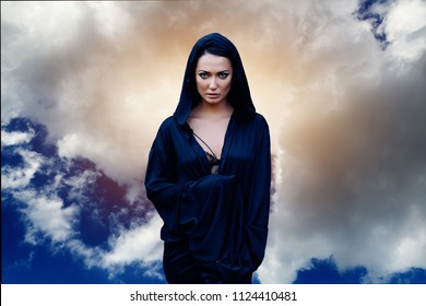 A Woman Is A Prophet Sorcerer And A Preacher In A Black Mystical Cloak With A Hood Against A Dramatic Background