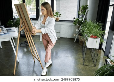 A woman with a prosthetic leg adjusts a canvas on an easel. - Powered by Shutterstock