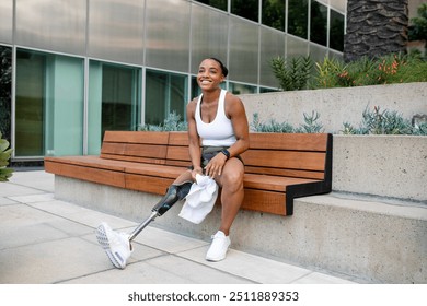 Woman with prosthetic leg carrying a towel sitting on the bench  - Powered by Shutterstock