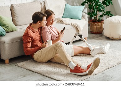 A woman with a prosthetic leg and her boyfriend relax on the floor, enjoying each others company. - Powered by Shutterstock