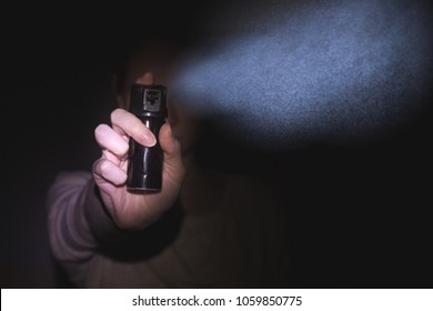a woman is protected by a gas pepper spray in the dark, a black background. concept of safety and self-defense