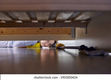 Woman In Protective Gloves Cleaning Floor Under Bed In Room Using Flat Wet Mop. House Cleaning.