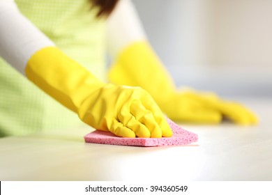 Woman In Protective Gloves Cleaning Kitchen Table With Rag