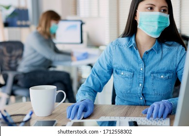 Frauen in Schutzhandschuhen und Masken im Büro