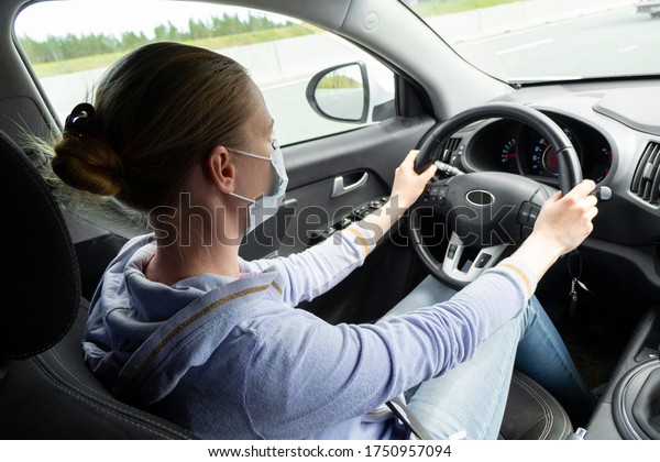 Woman in protective mask
driving a car. Coronavirus COVID-19 protection concept. Young woman
with protective face mask in the car. Surgery protective mask on
driver face.