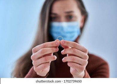 Woman In Protective Mask Holds Ring. Break Up Relationship After Living Together And Staying Home During Quarantine And Isolation Due To Coronavirus Covid Epidemic. Divorce Concept 