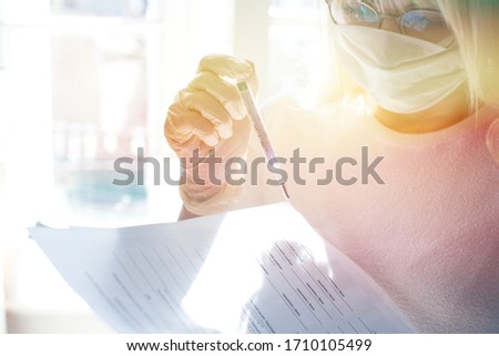 A woman in a protective mask in rubber gloves holding a thermometer in her hand. A woman wears a face mask that protects against coronavirus. Closeup of a woman with mask against SARS-cov-2.
