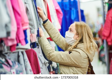 Woman In Protective Mask Shopping Clothing In Apparel Shop At Coronavirus Epidemic