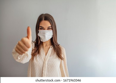 Woman with protective mask showing thumb up, and looking at camera. Woman with face mask protection of Coronavirus in human lungs. MERS-CoV, SARS, Adenoviruses and other respiratory viruses - Shutterstock ID 1671963346