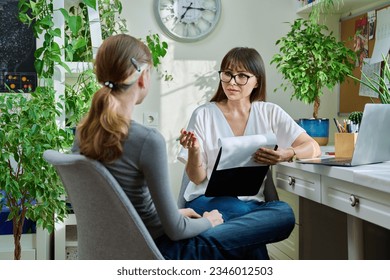 Woman psychologist, counselor talking with girl child - Shutterstock ID 2346012503