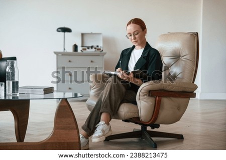 Woman psychologist in formal clothes is with notepad indoors.