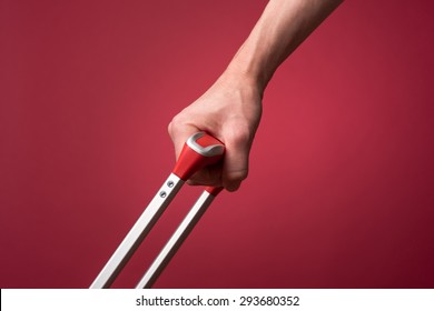 Woman pulling luggage by the handle. Photographed in front of a red backdrop with studio lighting. 