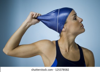 Woman Pulling Off Swim Cap Over Blue Background