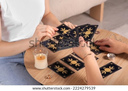 Woman pulling one tarot card at table indoors, closeup. Fortune telling