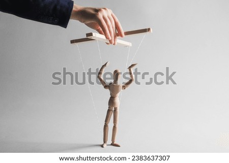 Woman pulling strings of puppet on light grey background, closeup