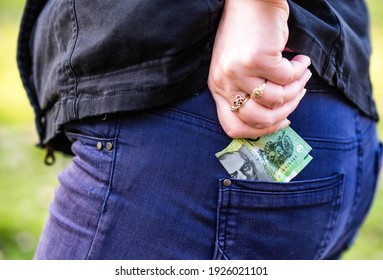 woman pulls Australian dollar paper money out of her pocket