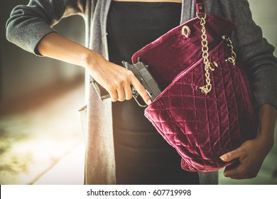 Woman Pulls A Gun From Her Swanky Purse. Conceal Carry Weapon For Protection Themselves Concept. Selective Focus To Gun.